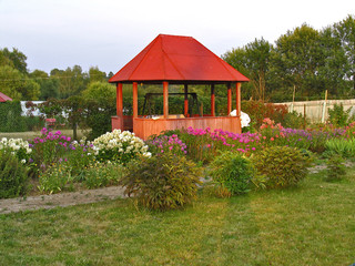 Wooden arbour in floral garden at sunset