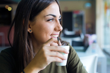Beautiful girl drinking coffee sitting indoor in urban cafe.