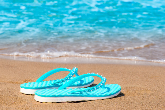 Turquoise flip flops abandoned on a sandy seashore