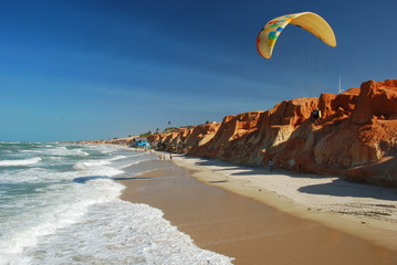 parapentiste volant entre plage et falaise