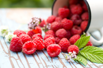 Fresh raspberries in a cup on old wooden table.