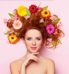 Beautiful redhead girl with flowers on pink background