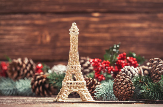 Eiffel tower toy with pine branches on a table.