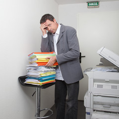un homme d'affaire fatigué et débordé devant tous les documents a traiter