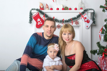 Happy young family  is sitting near  New Year  Christmas tree