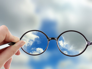 Fototapeta na wymiar Vision concept. Glasses in hand on sky background