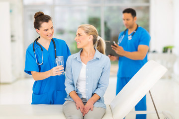 young medical intern offering senior patient water