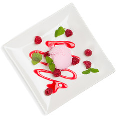Top view of pink ice cream scoop with sauce and berries of  rasp