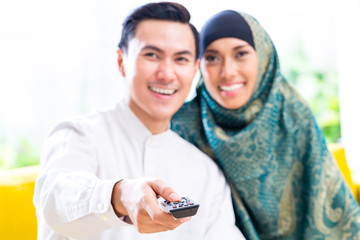 Asian Muslim Couple switching TV with remote control