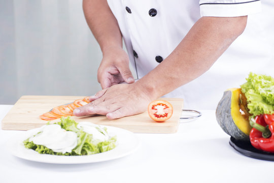 Chef's hands cutting Tomato