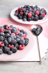 Iced berries on plate, on color wooden background