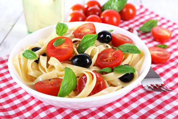 Spaghetti with tomatoes, olives and basil leaves