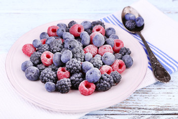 Iced berries on plate, on color wooden background