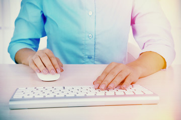 Female hands typing on keyboard on light background