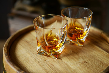 Glasses of brandy in cellar with old barrels