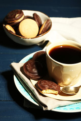 Cup of coffee with tasty cookies on color wooden background