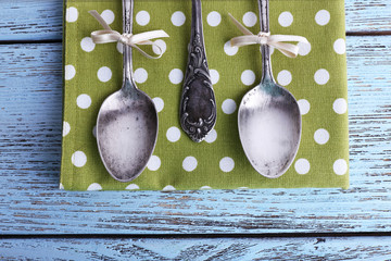 Metal spoons on green polka dot napkin on wooden background
