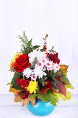 Flower bouquet in blue vase on light wooden background