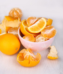 Fototapeta na wymiar Sweet tangerines and oranges on table in bowl in room