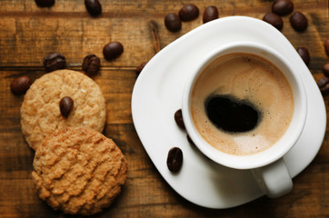 Cup of espresso and tasty cookie on wooden background
