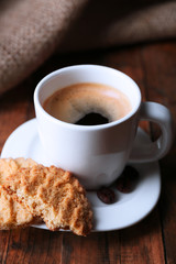 Cup of espresso and tasty cookie on wooden background