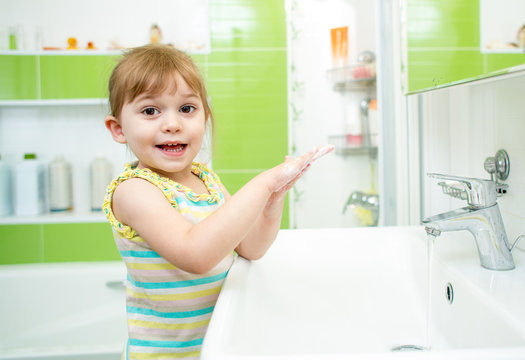 Cute little girl washing in bathroom