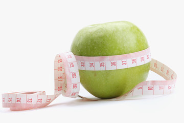 A green apple and a measuring tape