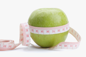 A green apple and a measurement tape , isolated on white