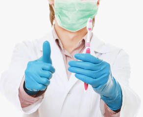 A male dentist with a toothbrush and showing ok , isolated on