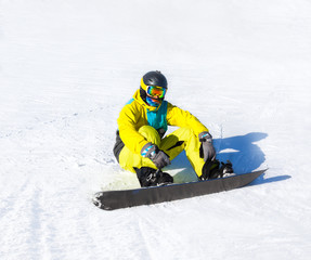 Snowboarder sitting on snow mountains