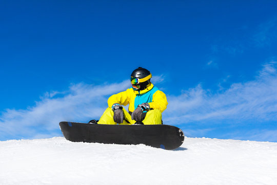 snowboarder sitting on snow mountain slope