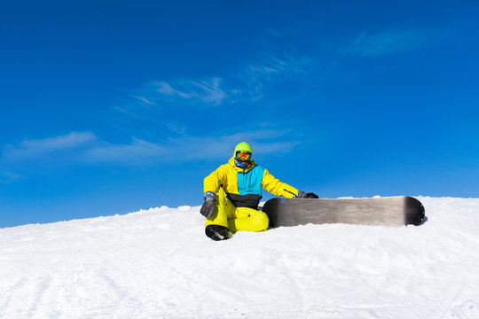 snowboarder sitting on snow mountain slope
