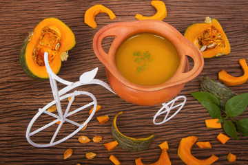 Pumpkin soup in clay pot with fresh pumpkins for healthy