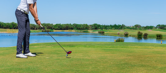 Man simulates play golf. With the stick on the green field.