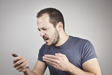 angry young man while answering smart phone not understood