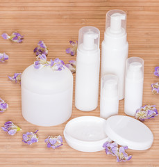Fototapeta na wymiar Open jar of cream and other body care cosmetics with flowers