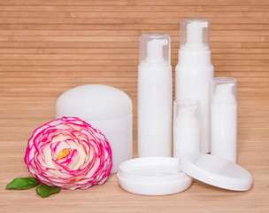 Fototapeta na wymiar Open jar of cream and other body care cosmetics with a flower