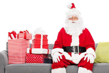 Santa sitting on a sofa full of Christmas presents