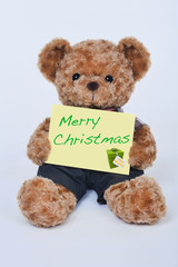 Teddy bear holding a  sign that says Merry Christmas