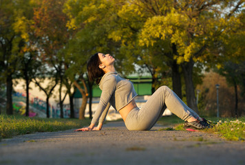 Sports woman sitting in park relaxing