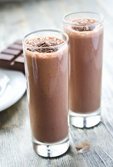 Chocolate smoothie in glasses on wooden background