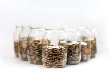 coins in a three glass jars against a white background - 72872328