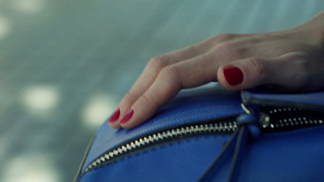 Close up of woman fingers tapping handbag 