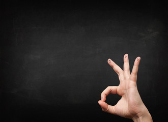 Happy smiley fingers looking at empty black chalboard