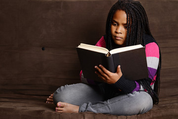 child reading book sitting on couch
