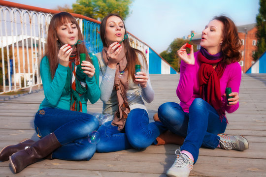 Three Young Beautiful Women Blow Bubbles