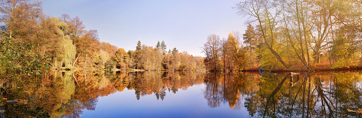 panorama of autumn trees at a glassy lake