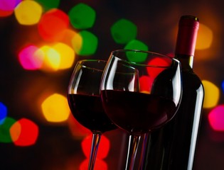 red wine glasses near bottle on colorful bokeh lights background