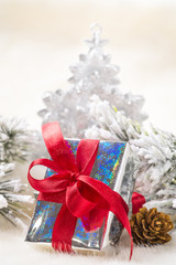 Christmas gift with red ribbon on background of fir branches