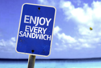 Enjoy Every Sandwich sign with a beach on background